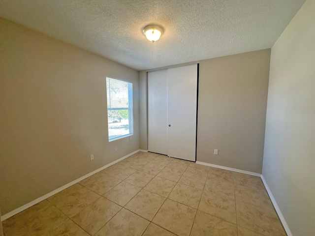 tiled empty room with a textured ceiling