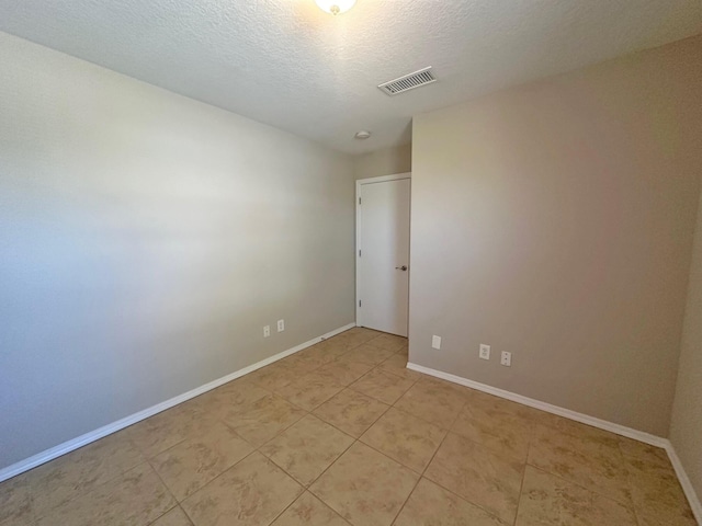 tiled empty room with a textured ceiling