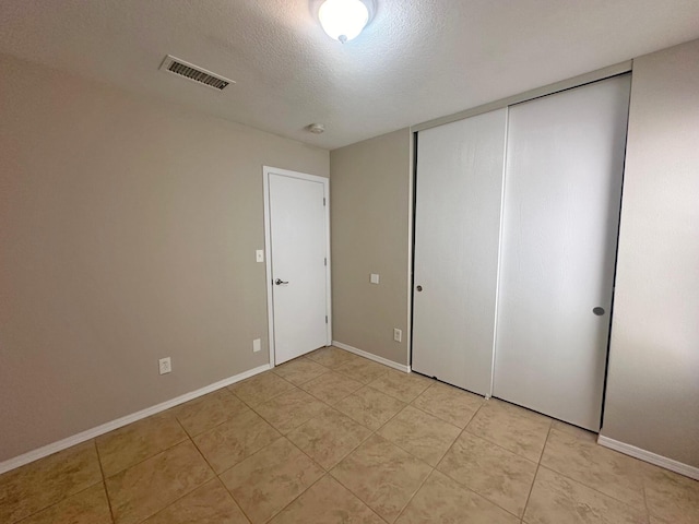 unfurnished bedroom with a textured ceiling and a closet