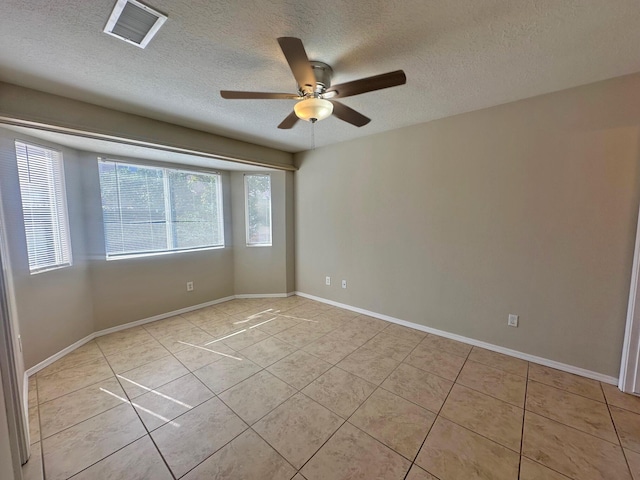 tiled empty room featuring ceiling fan, plenty of natural light, and a textured ceiling