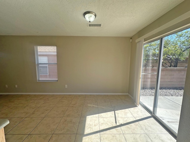 tiled empty room with a textured ceiling