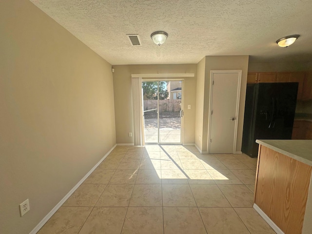 unfurnished dining area with light tile patterned floors and a textured ceiling