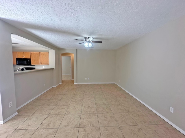 unfurnished living room with ceiling fan, light tile patterned floors, and a textured ceiling