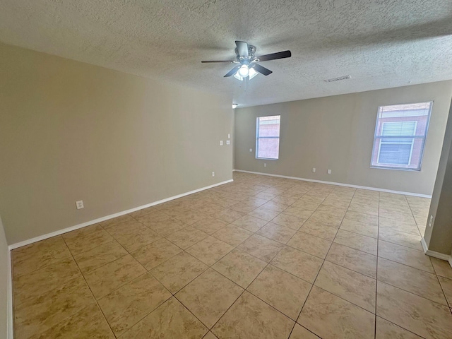 tiled empty room with ceiling fan and a textured ceiling