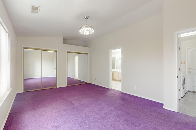 unfurnished bedroom featuring connected bathroom, multiple closets, light carpet, and lofted ceiling