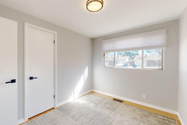 empty room featuring visible vents, baseboards, and wood finished floors