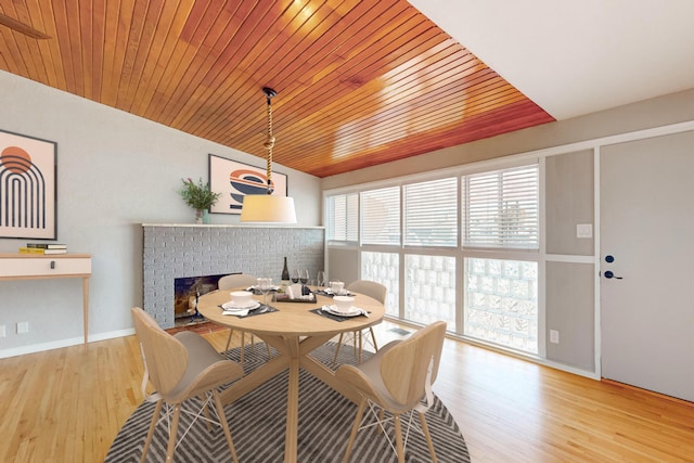 dining area with a brick fireplace, wood ceiling, baseboards, and wood finished floors