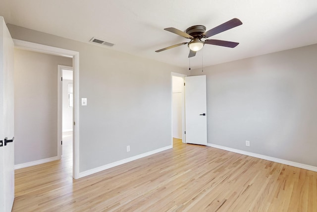 empty room featuring light wood finished floors, baseboards, and visible vents