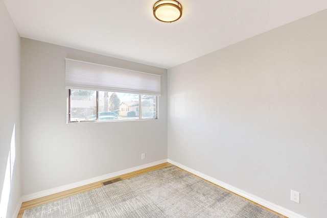 unfurnished room featuring visible vents, baseboards, and wood finished floors