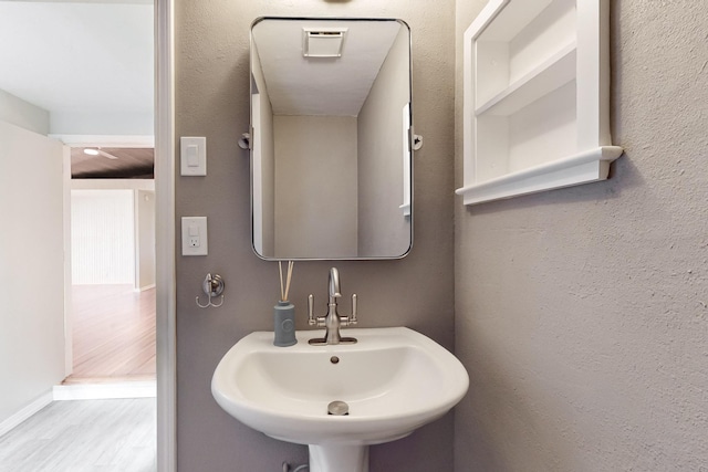 bathroom with wood finished floors, a sink, and baseboards