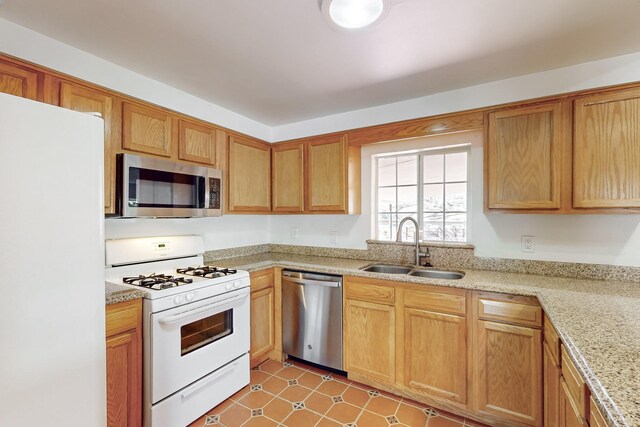 kitchen featuring light stone counters, sink, stainless steel appliances, and light tile patterned flooring