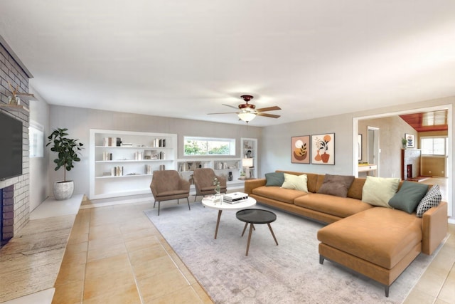 living room with a brick fireplace, built in shelves, a wealth of natural light, and tile patterned floors