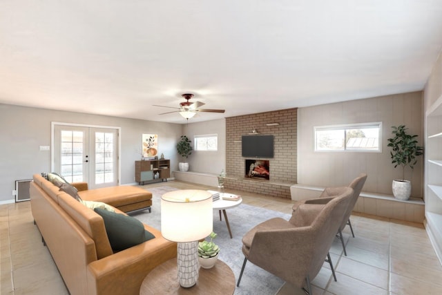 living room featuring french doors, ceiling fan, a brick fireplace, and light tile patterned floors