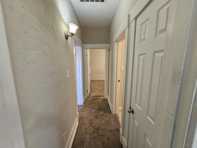 hallway featuring dark colored carpet