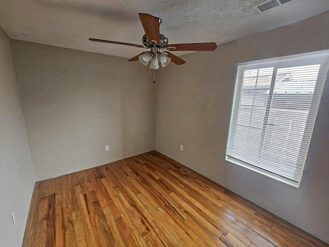 spare room with a textured ceiling, light wood-type flooring, and ceiling fan