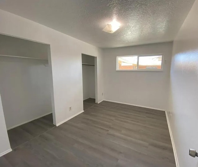 unfurnished bedroom with a textured ceiling and dark wood-type flooring