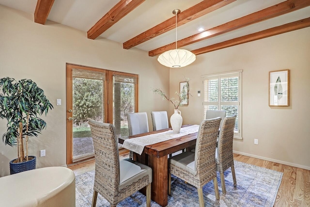 dining space featuring beamed ceiling and light wood-type flooring