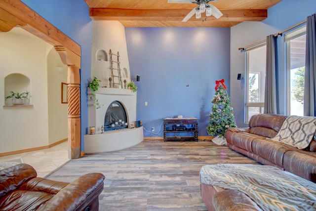 living room featuring ceiling fan, light hardwood / wood-style flooring, beamed ceiling, and wood ceiling