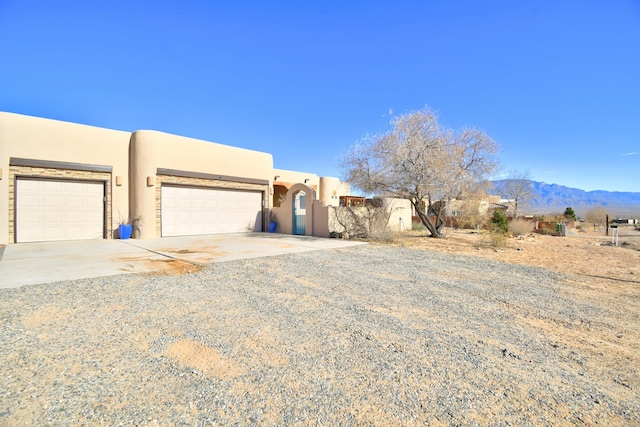 pueblo-style home with a mountain view and a garage