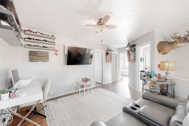 living room featuring ceiling fan, a textured ceiling, and hardwood / wood-style flooring