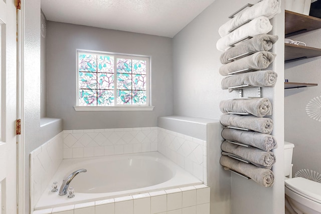 bathroom featuring tiled bath and toilet