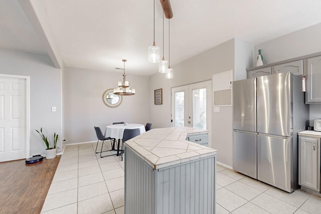 kitchen with stainless steel refrigerator, light tile patterned flooring, gray cabinets, and pendant lighting