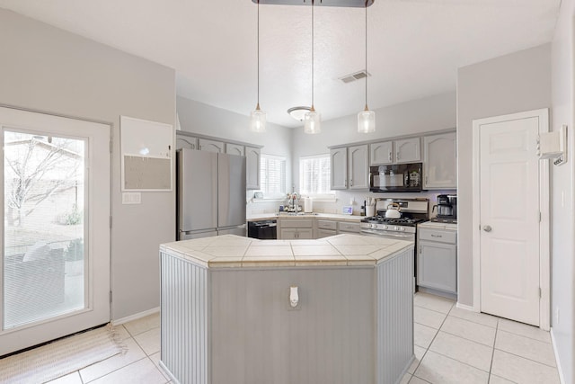 kitchen featuring light tile patterned floors, hanging light fixtures, gray cabinetry, and black appliances