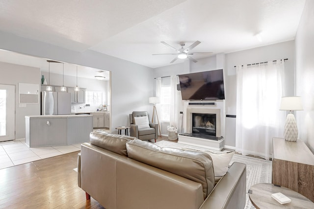 living room featuring sink, light hardwood / wood-style flooring, plenty of natural light, and ceiling fan