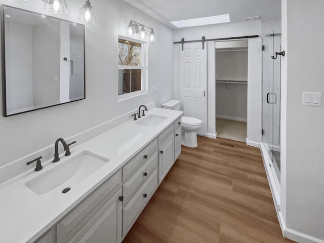 bathroom featuring vanity, toilet, wood-type flooring, and a shower with door