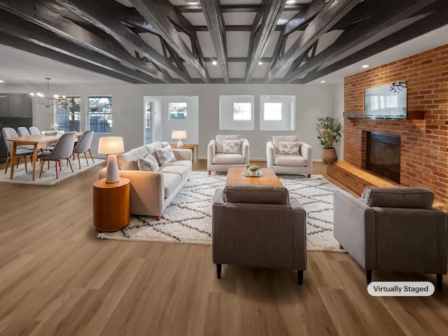 living room featuring a notable chandelier, light hardwood / wood-style floors, beam ceiling, and a fireplace