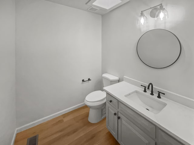 bathroom with toilet, vanity, and hardwood / wood-style flooring