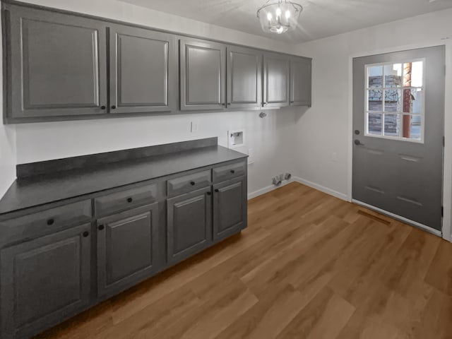 laundry area featuring washer hookup, a chandelier, cabinets, and light hardwood / wood-style flooring