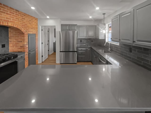 kitchen featuring gray cabinetry, sink, stainless steel appliances, and hanging light fixtures