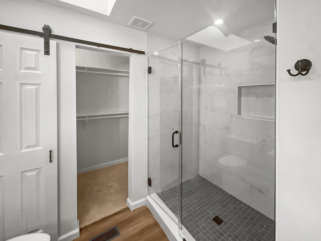 bathroom with a shower with door, hardwood / wood-style floors, and toilet