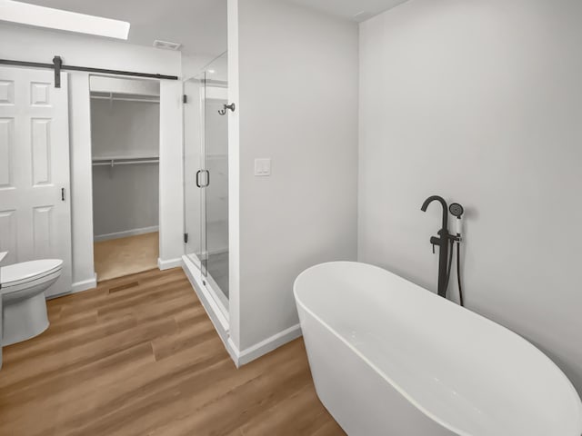 bathroom featuring toilet, hardwood / wood-style floors, and shower with separate bathtub