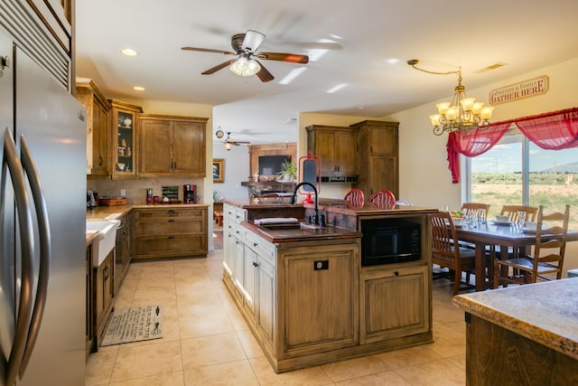 kitchen with ceiling fan with notable chandelier, sink, built in appliances, decorative light fixtures, and light tile patterned flooring