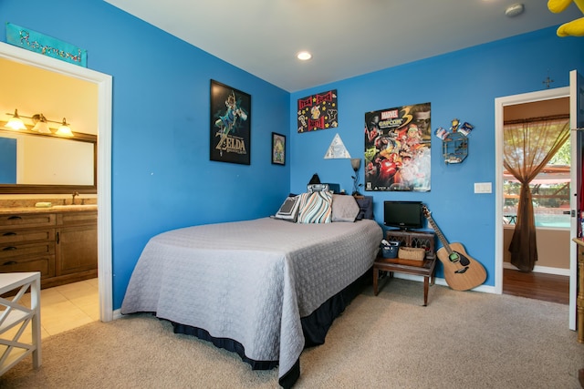 carpeted bedroom featuring connected bathroom and sink