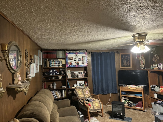 carpeted living room featuring a textured ceiling, ceiling fan, and wood walls