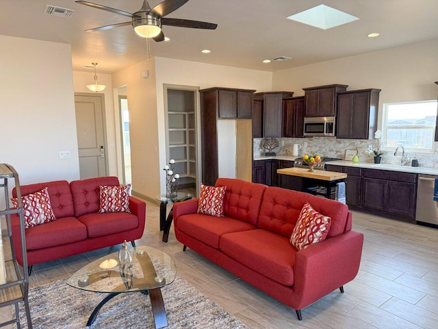 living room with sink, ceiling fan, and a skylight