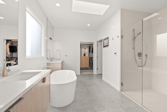 bathroom with vanity, shower with separate bathtub, and a skylight