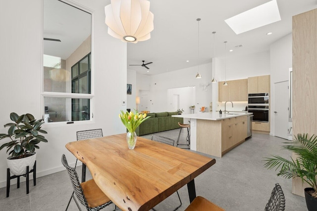 dining area featuring ceiling fan, sink, and a skylight