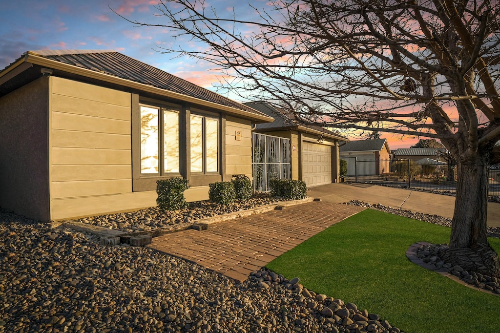 property exterior at dusk featuring a garage and a yard