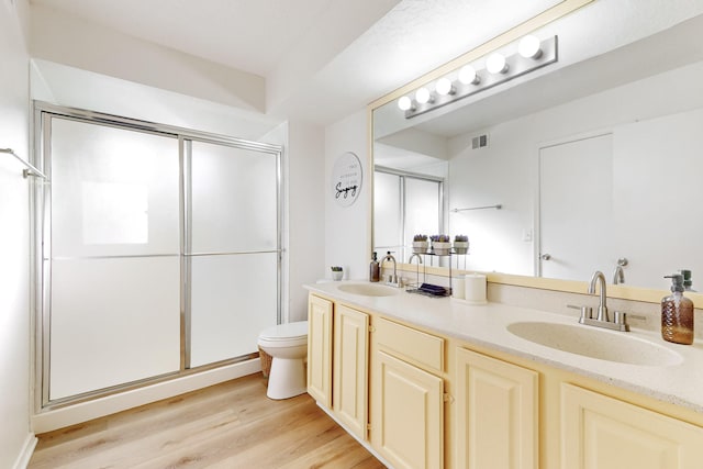 bathroom with hardwood / wood-style floors, vanity, an enclosed shower, and toilet