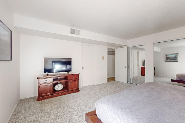 bedroom featuring light carpet and two closets