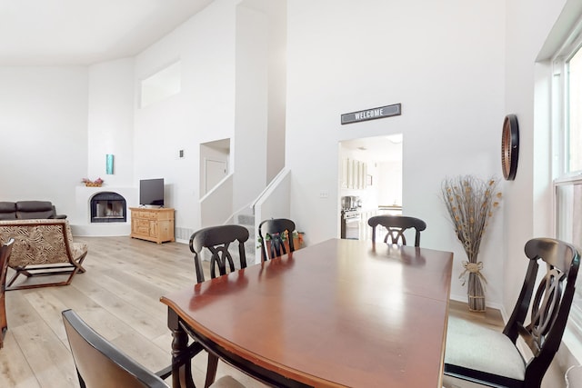 dining space with a high ceiling and light hardwood / wood-style flooring