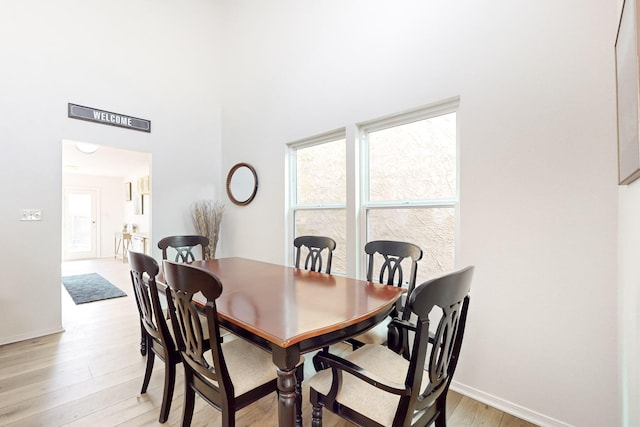 dining area featuring a towering ceiling and light hardwood / wood-style floors