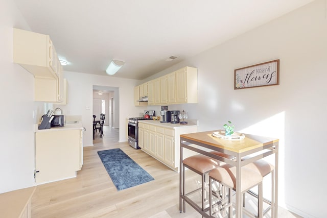 kitchen with stainless steel gas range oven and light hardwood / wood-style flooring