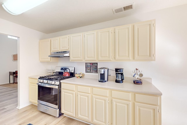 kitchen featuring cream cabinetry, gas range, and light wood-type flooring