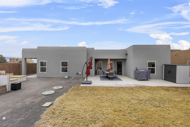 back of property featuring a lawn, a patio, fence, and stucco siding