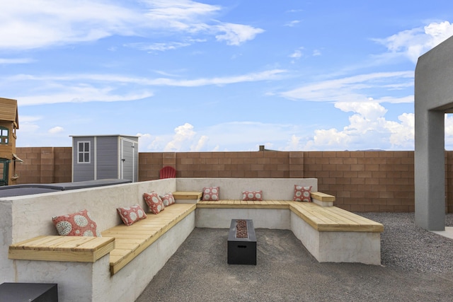 view of patio / terrace featuring an outdoor fire pit, a fenced backyard, an outdoor structure, and a shed